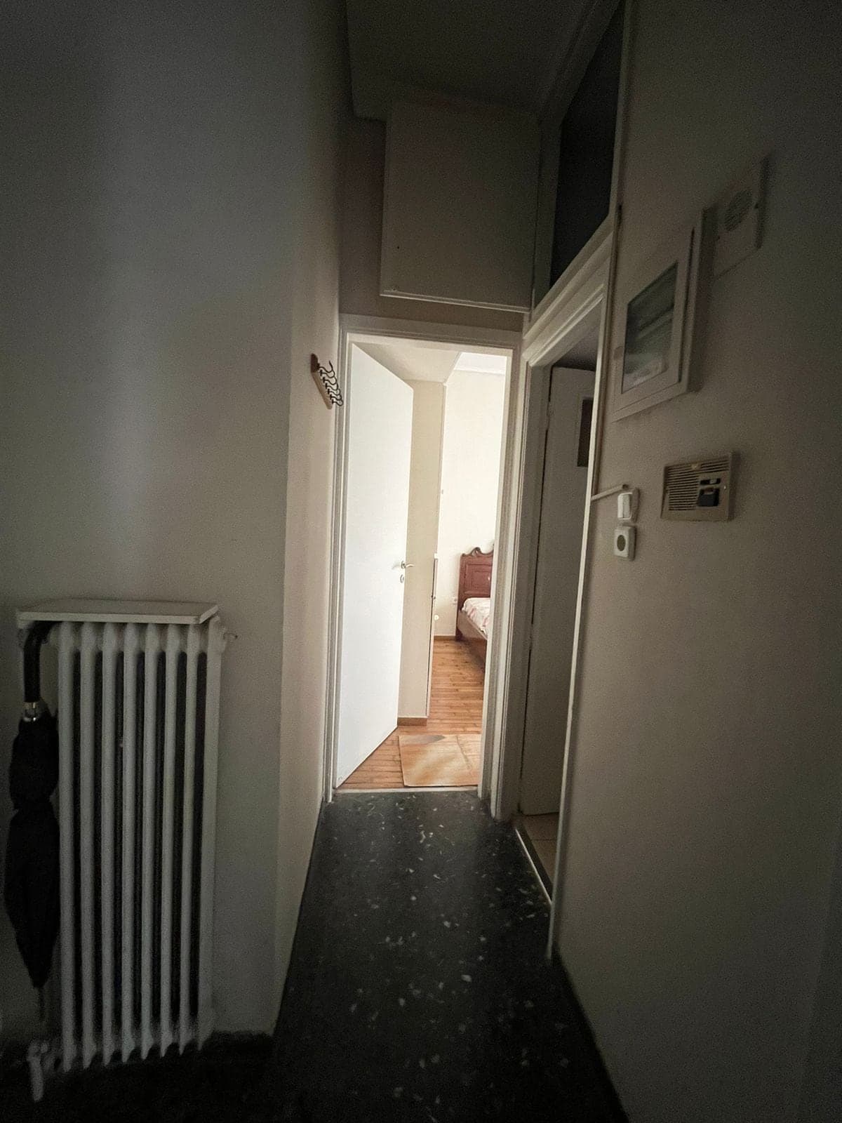 Hallway before renovation, dim, with an old radiator and dark floor