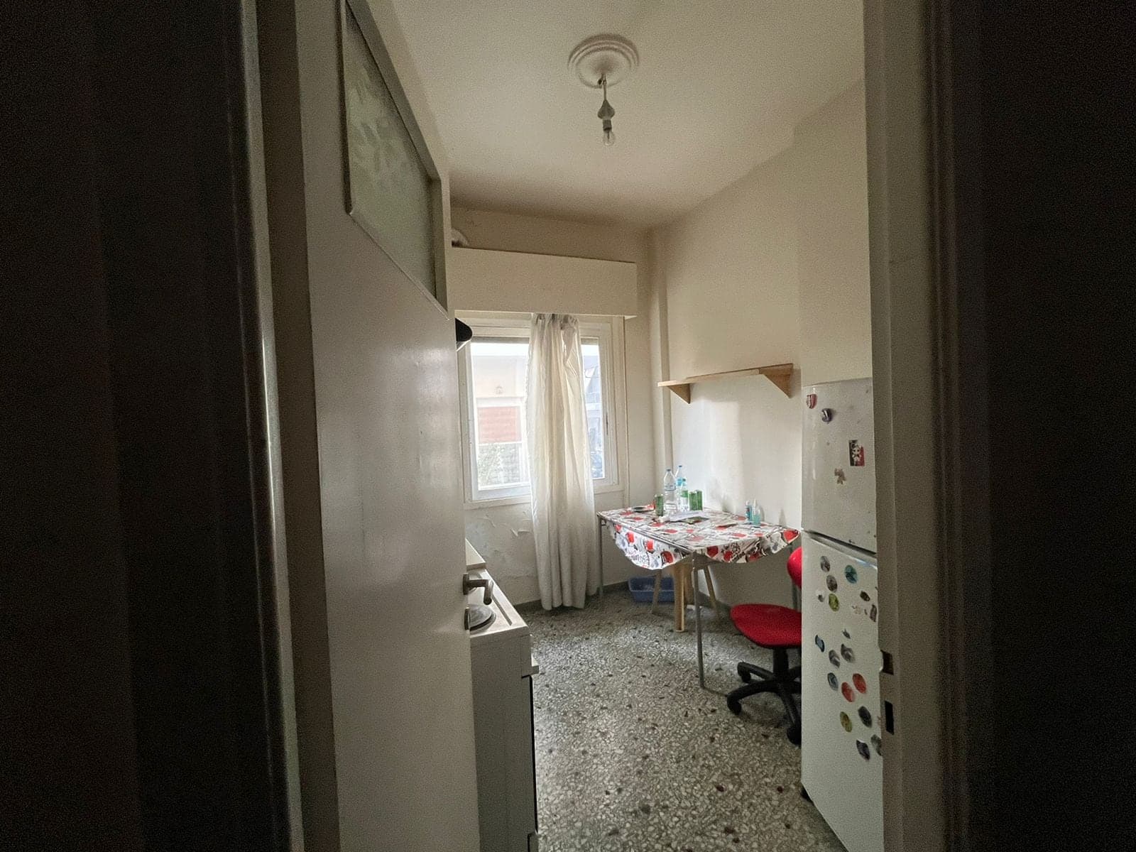 Narrow kitchen before renovation with mosaic floor and a small table